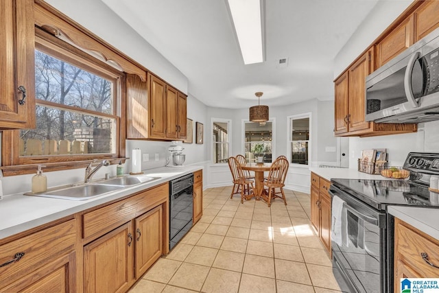 kitchen with black appliances, hanging light fixtures, light tile patterned flooring, and sink