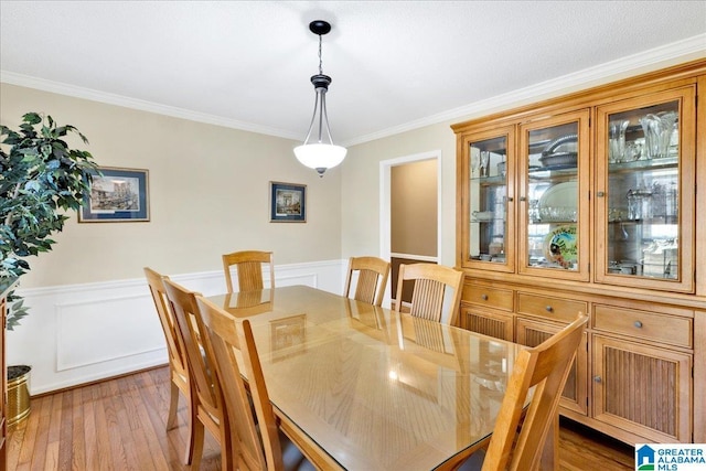 dining space with ornamental molding and light hardwood / wood-style floors