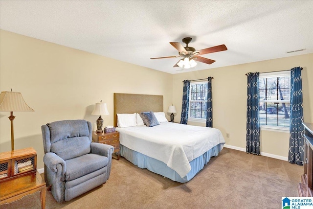 bedroom featuring light colored carpet, ceiling fan, and a textured ceiling