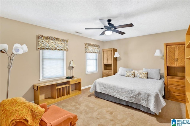 bedroom with a textured ceiling, ceiling fan, and light carpet