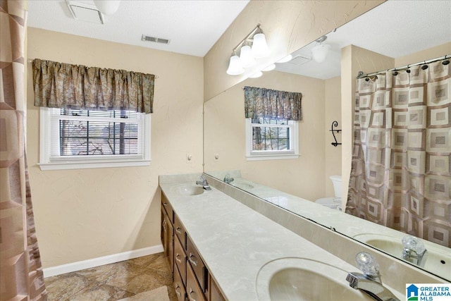 bathroom featuring toilet, a healthy amount of sunlight, and vanity