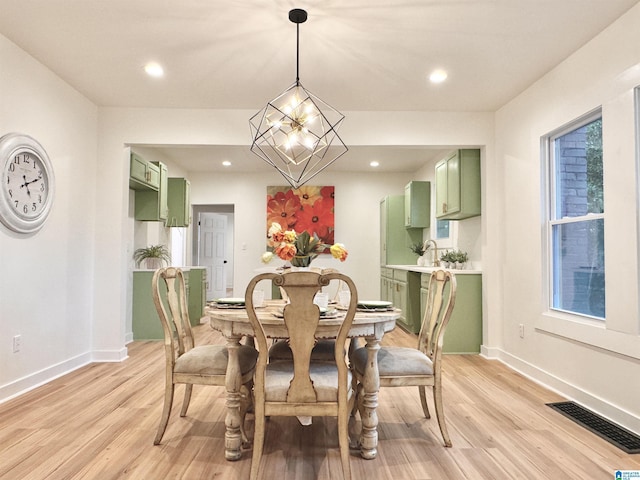 dining area with a healthy amount of sunlight, light hardwood / wood-style flooring, and a notable chandelier