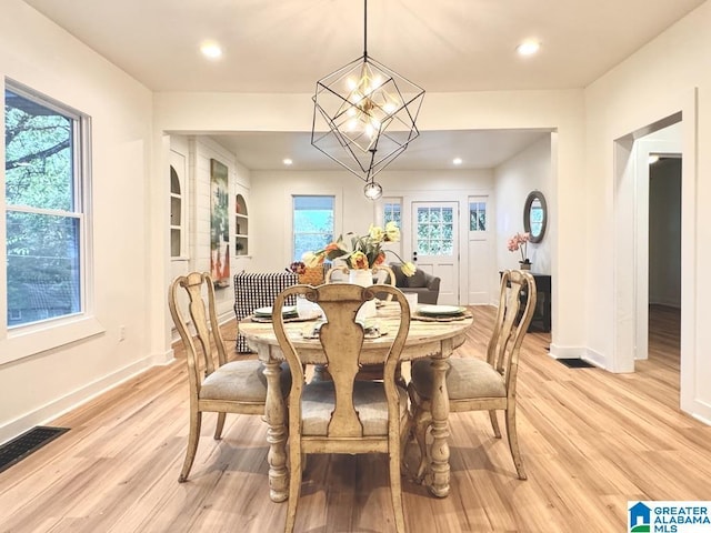 dining space with light wood-type flooring and a notable chandelier