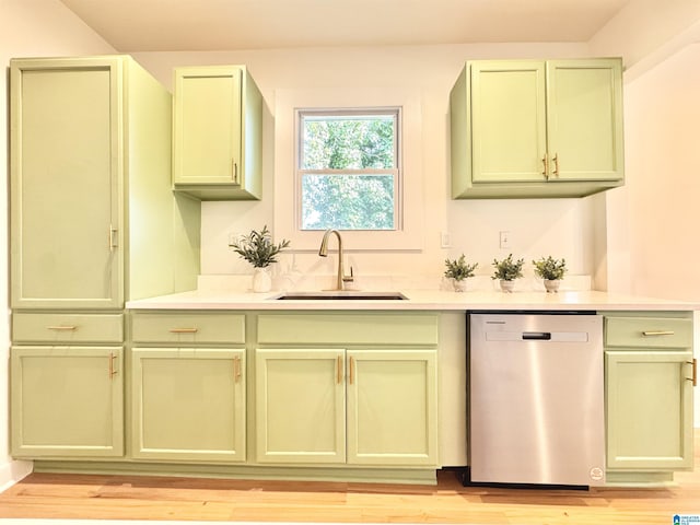 kitchen featuring stainless steel dishwasher, green cabinetry, sink, and light wood-type flooring