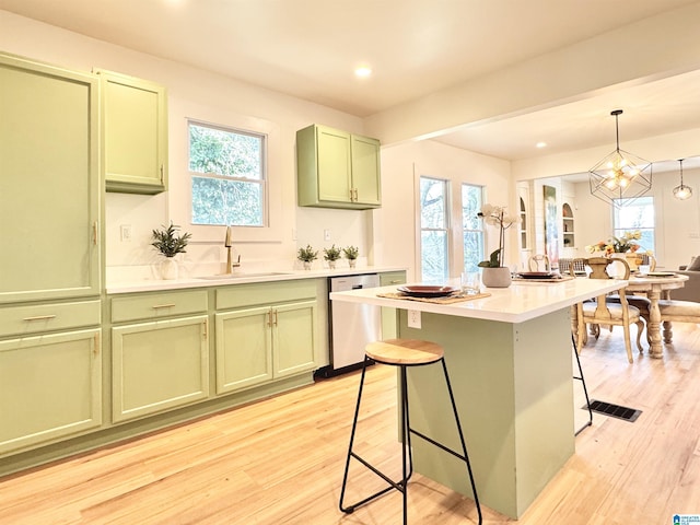 kitchen featuring dishwasher, green cabinets, decorative light fixtures, a breakfast bar, and sink