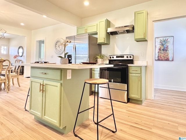 kitchen featuring stainless steel appliances, a breakfast bar area, light hardwood / wood-style flooring, and green cabinets