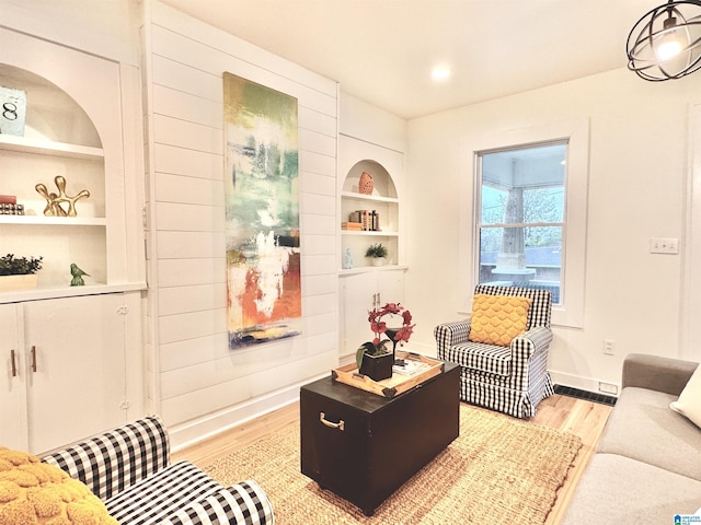 living room featuring built in shelves and light hardwood / wood-style flooring