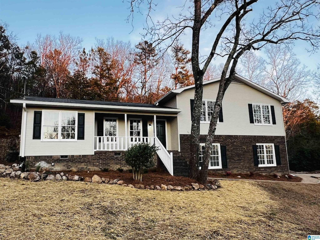 tri-level home featuring a front yard and covered porch