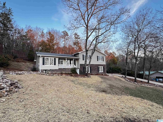 tri-level home featuring covered porch and a front yard