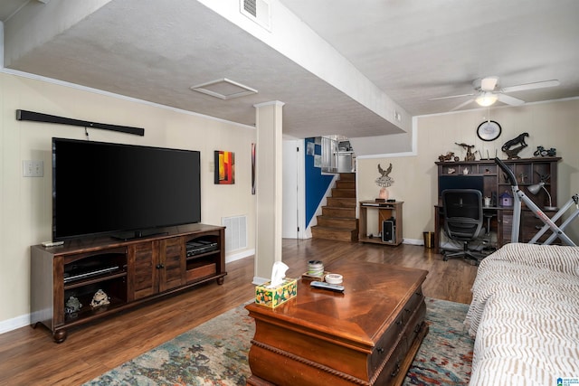 living room featuring ceiling fan, ornamental molding, dark wood-type flooring, and a textured ceiling