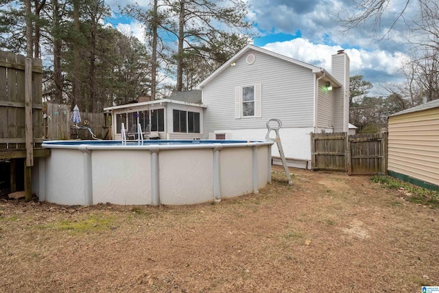 back of property with a fenced in pool, a yard, and a sunroom