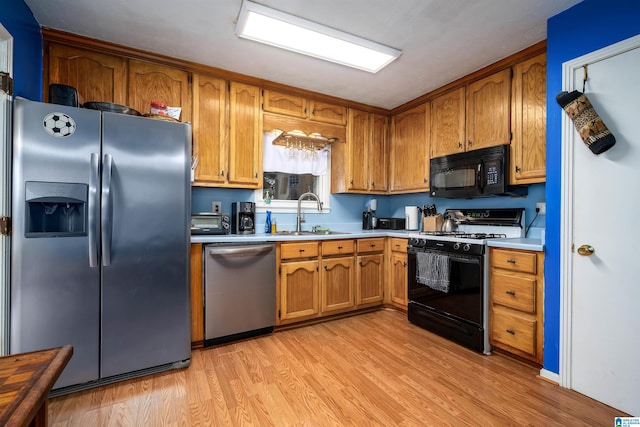 kitchen with sink, black appliances, and light wood-type flooring