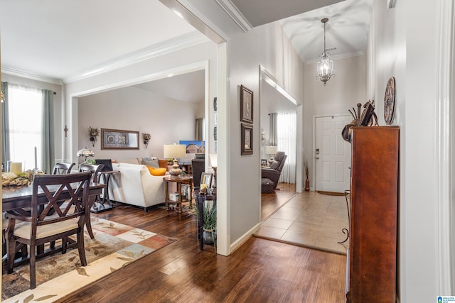 foyer with an inviting chandelier, ornamental molding, and dark wood-type flooring