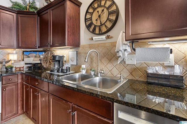 kitchen with dark stone counters, light tile patterned floors, tasteful backsplash, and sink