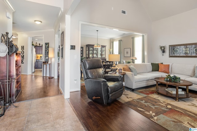 tiled living room with ornamental molding and vaulted ceiling