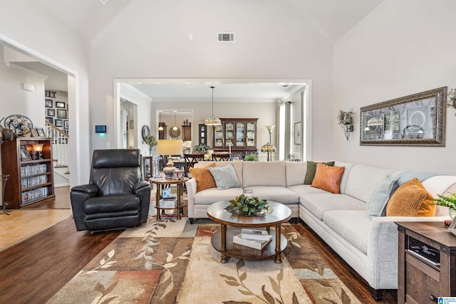 living room with high vaulted ceiling, crown molding, and dark hardwood / wood-style floors