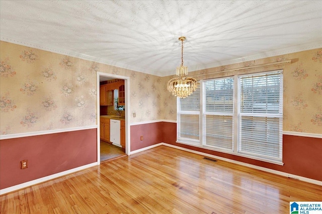 unfurnished room with light wood-type flooring, a chandelier, and ornamental molding