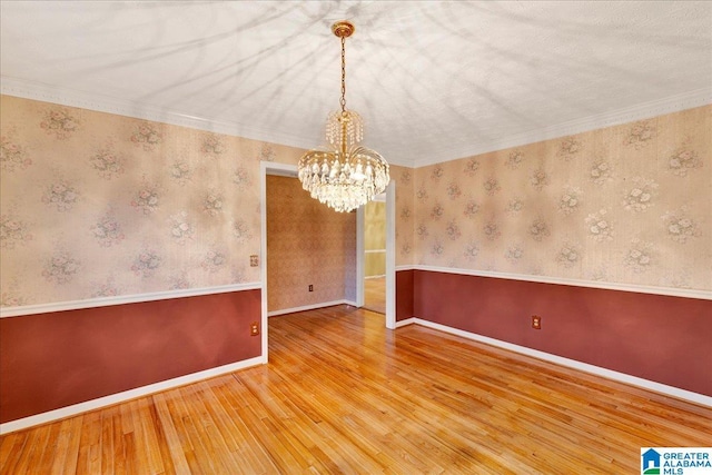 unfurnished room with an inviting chandelier, ornamental molding, and wood-type flooring