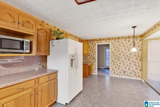 kitchen featuring decorative light fixtures, white fridge with ice dispenser, and a textured ceiling