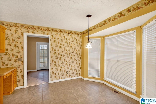 unfurnished dining area with tile patterned floors and a textured ceiling