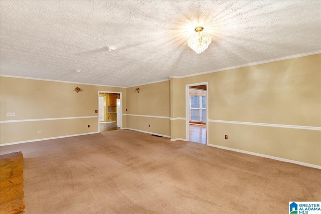 carpeted spare room featuring a textured ceiling, ornamental molding, and a notable chandelier