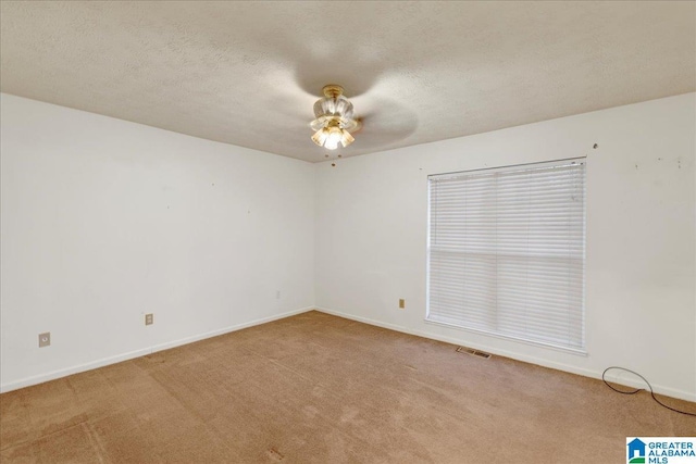 empty room with ceiling fan, a textured ceiling, and light carpet