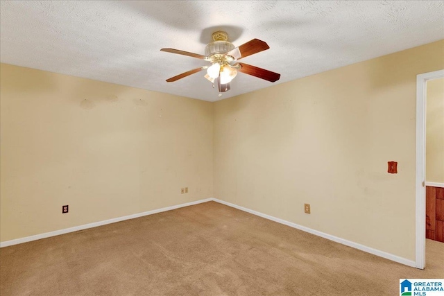 spare room with ceiling fan, a textured ceiling, and light carpet