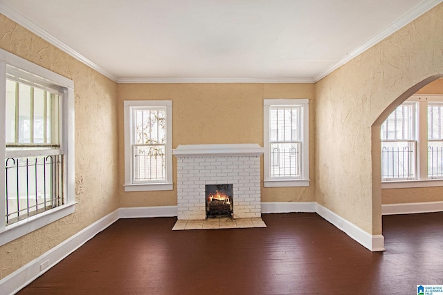 unfurnished living room featuring a fireplace, crown molding, dark hardwood / wood-style flooring, and plenty of natural light