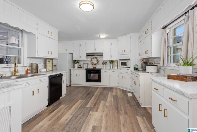 kitchen featuring white appliances, white cabinets, light wood-type flooring, and backsplash