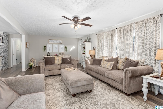 living room with a textured ceiling, ceiling fan, and light hardwood / wood-style flooring