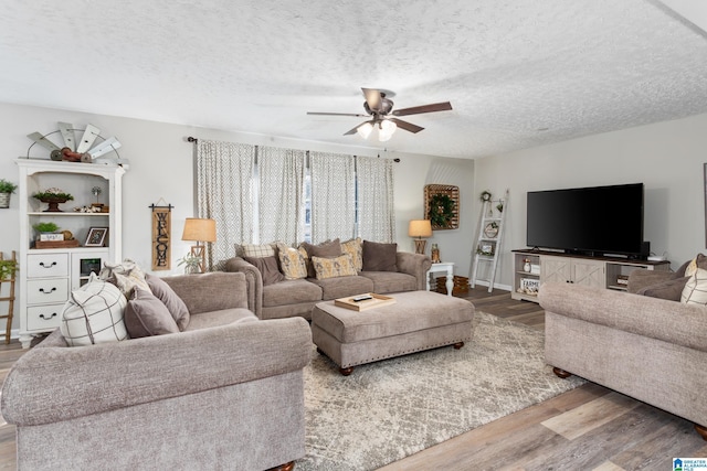 living room with a textured ceiling, ceiling fan, and hardwood / wood-style flooring