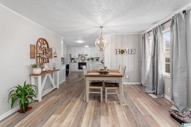 dining space featuring a textured ceiling, light wood-type flooring, and an inviting chandelier