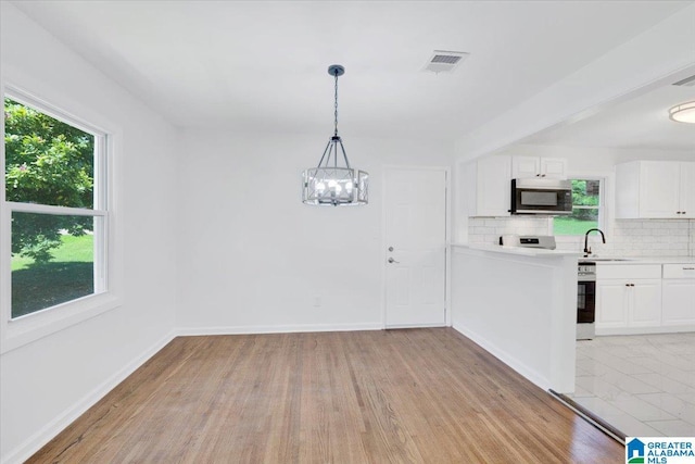 kitchen featuring white cabinetry, a healthy amount of sunlight, tasteful backsplash, and hanging light fixtures