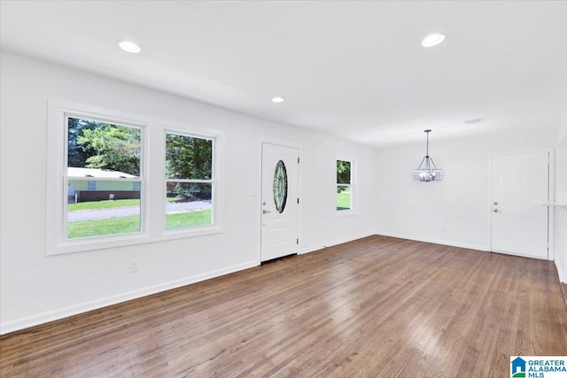 entrance foyer featuring hardwood / wood-style flooring, an inviting chandelier, and plenty of natural light