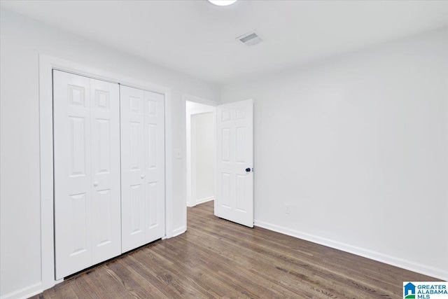 unfurnished bedroom with a closet and dark wood-type flooring