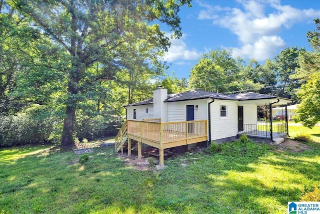 rear view of house with a wooden deck and a lawn