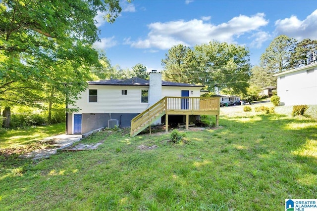 rear view of property featuring a lawn, cooling unit, and a wooden deck