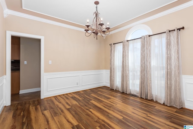 spare room with dark wood-type flooring, ornamental molding, and a chandelier