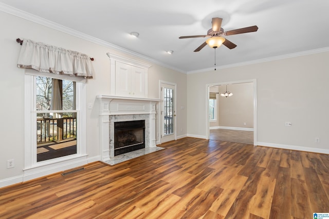 unfurnished living room with ceiling fan with notable chandelier, dark wood-type flooring, ornamental molding, and a fireplace