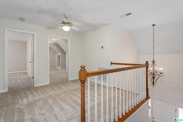 corridor featuring vaulted ceiling, an inviting chandelier, and light carpet