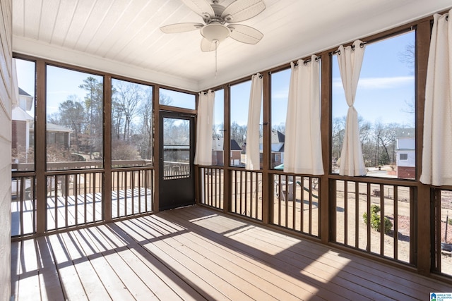 unfurnished sunroom featuring ceiling fan, plenty of natural light, and wooden ceiling