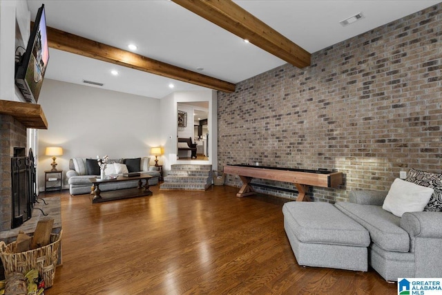 living room with brick wall, wood-type flooring, and beam ceiling