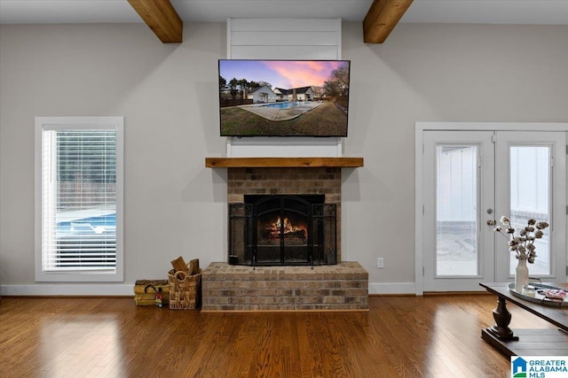 living room with french doors, a brick fireplace, wood-type flooring, and beam ceiling