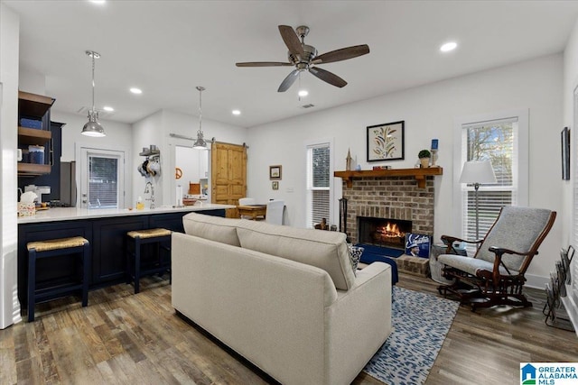 living room featuring ceiling fan, a brick fireplace, sink, and dark hardwood / wood-style floors