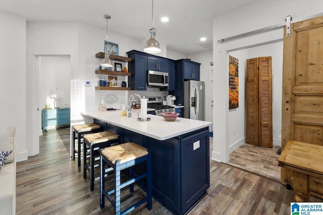 kitchen featuring a barn door, stainless steel appliances, kitchen peninsula, a kitchen bar, and decorative backsplash