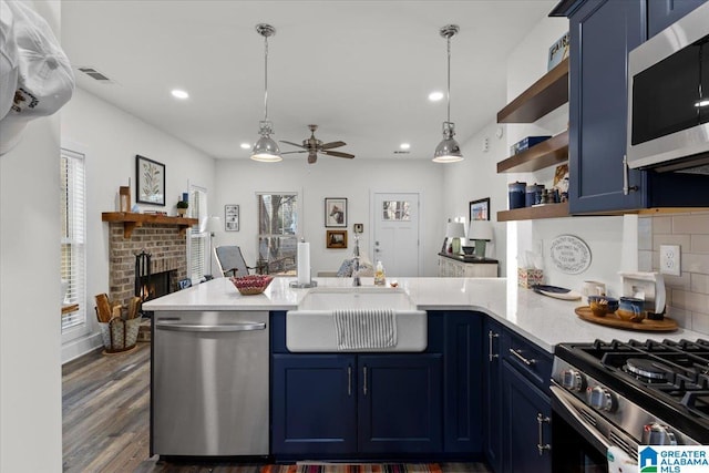 kitchen with stainless steel appliances, a brick fireplace, and blue cabinetry