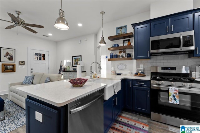 kitchen featuring sink, blue cabinetry, kitchen peninsula, and appliances with stainless steel finishes