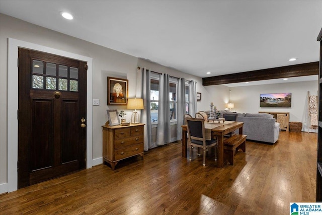 dining area featuring beam ceiling, dark wood-type flooring, and plenty of natural light