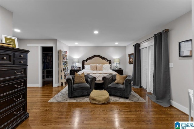 bedroom featuring a walk in closet, dark hardwood / wood-style flooring, and a closet