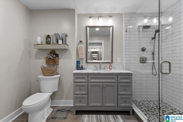 bathroom featuring toilet, a shower with door, and vanity